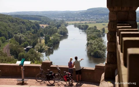 Eine Frau und ein Mann mit Rädern schauen von oben auf das Wasser